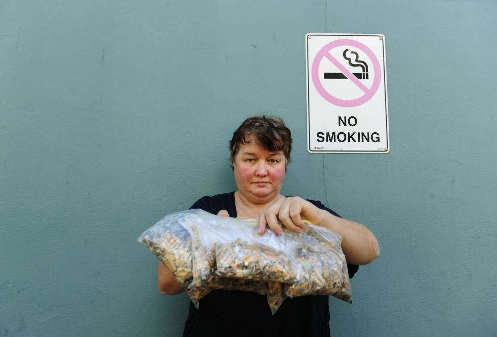 Action on Smoking and Health treasurer Terri Henderson holds sandwich bags filled with cigarette butts collected outside Canberra Hospital. Photo: Melissa Adams