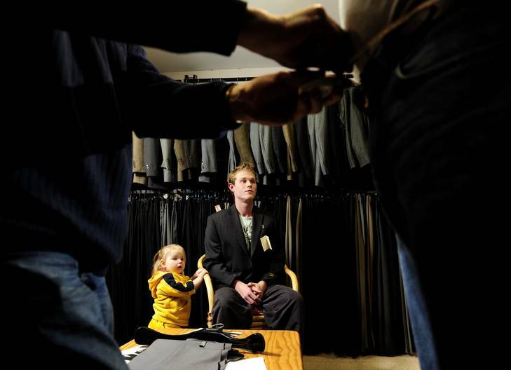 Latoya Webb (18 months) waits patiently with father and groom-to-be Luke Webb as Harry Statos of Kevin O'Connor Menswear in Queanbeyan measures up his groomsmen. Photo: Stuart Walmsley