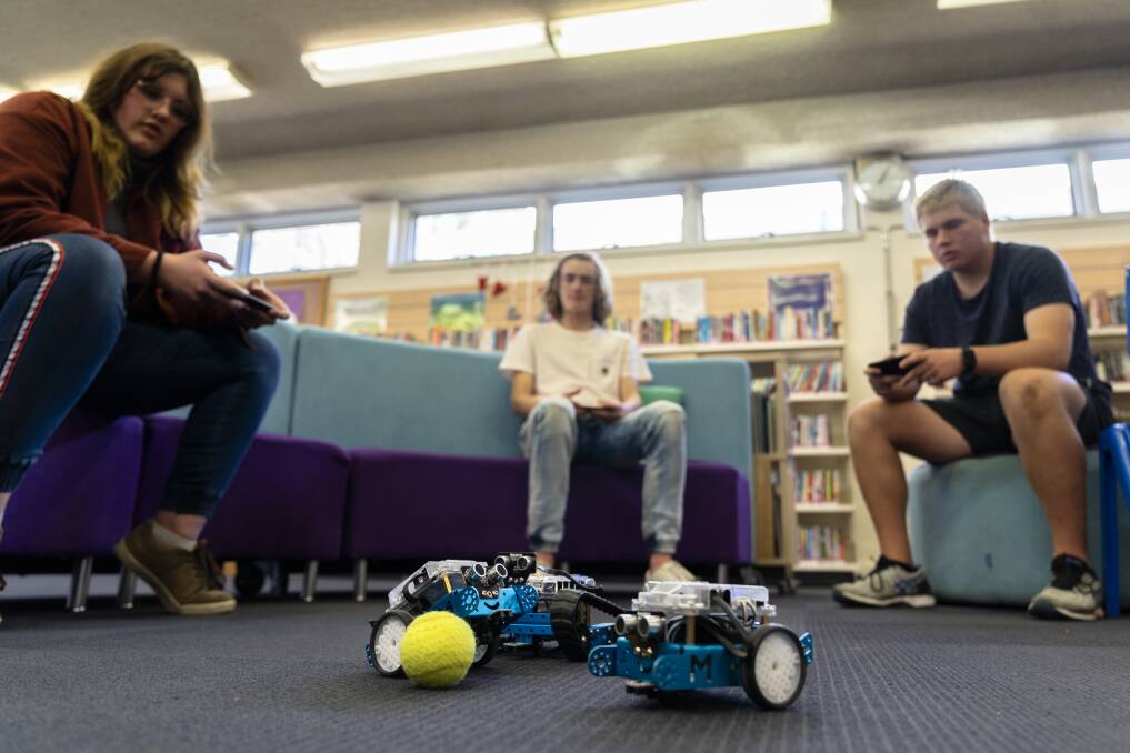 Alfred Deakin High School Year 10 students Shanti Geoghegan (left), Tom Hilton, and Liam Ayres play a game of soccer with their phone operated robots. Photo: Lawrence Atkin
