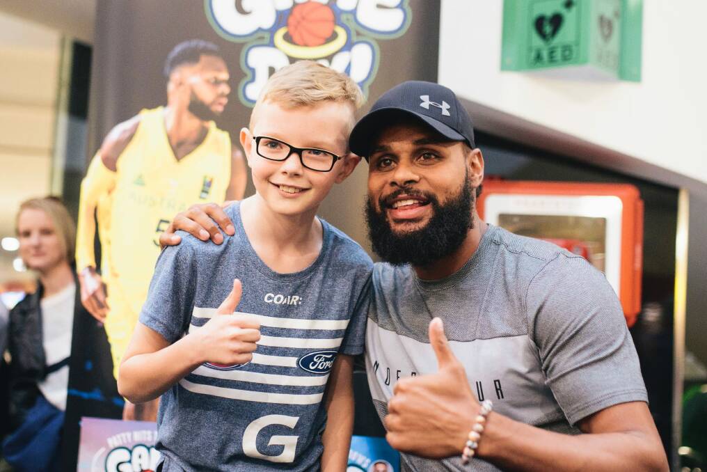 Patty Mills at Belconnen for a book signing for his new book Game Day. Patty Mills congratulates Logan Harrison after Logan beat Mills in a shootout. Photo: Rohan Thomson