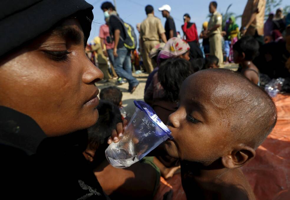 A Rohingya migrant mother watches as her child drinks water after they arrived in Indonesia by boat. Photo: Reuters
