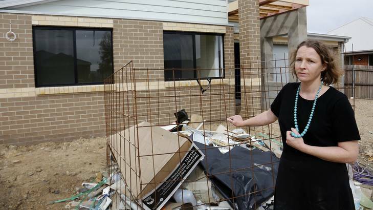 Courtenay Trinder, at her Ivy Kent Road home in Forde, next to rubbish left in front of her unfinished house.  Metro Construction and Development was supposed to finish the house in June but are now in administration. Photo: Jeffrey Chan