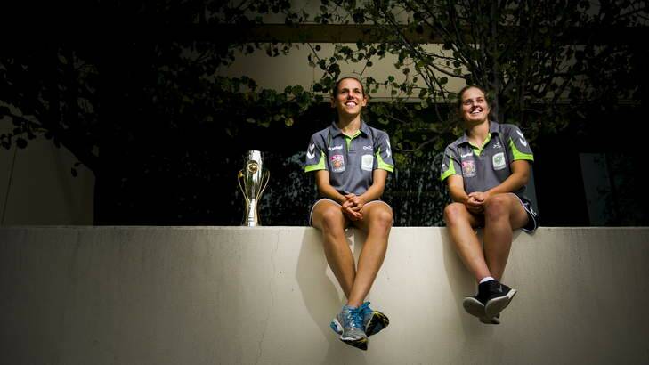 Canberra United players Nicole Sykes and Ellie Brush with the 2012 W-League trophy ahead of their semi-final against Brisbane this weekend. Photo: Rohan Thomson