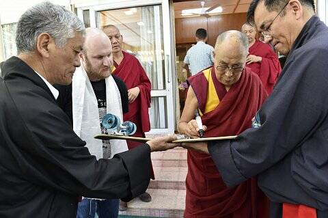 The Dalai Lama signs Aleks Stocki's skateboard. Photo: Supplied 