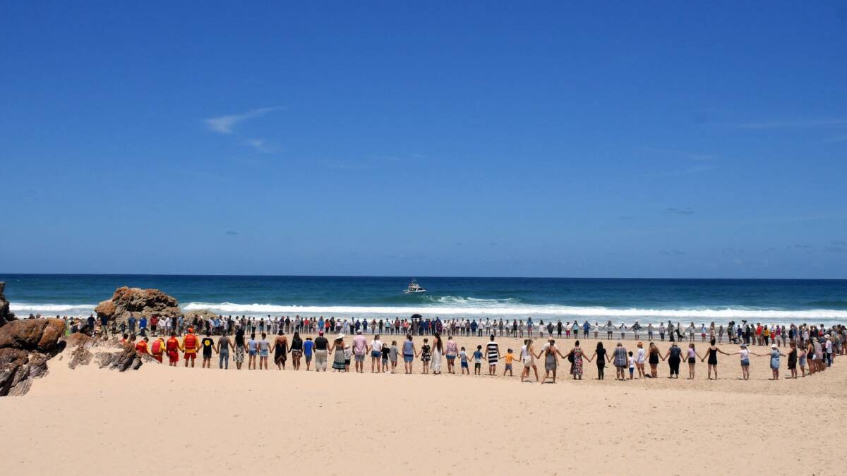 People gather on Lighthouse Beach near Port Macquarie to show support for the family of an 11-year-old boy from the ACT who was swept out to sea. Photo: Port Macquarie News