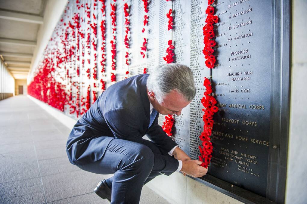 National War Memorial director, Brendan Nelson places a poppy on the Roll of Honor for the first soldier killed. Photo: Rohan Thomson