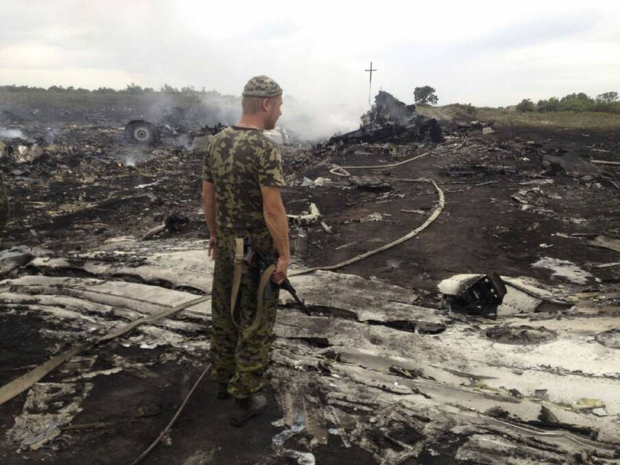 An armed pro-Russian separatist stands at the crash site of MH17 in the settlement of Grabovo, eastern Ukraine, last year. The missile strike killed 298 on board, including 39 Australians. Photo: Reuters