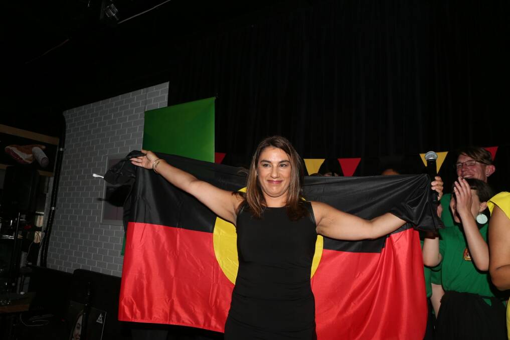 New Indigenous MP Lidia Thorpe, draped in the Aboriginal flag, celebrates her win in Northcote. Photo: Tom Cowie