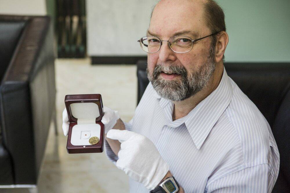 Reference librarian Andrew Sergeant, holding the world's smallest book at the National Library. Photo: Jamila Toderas