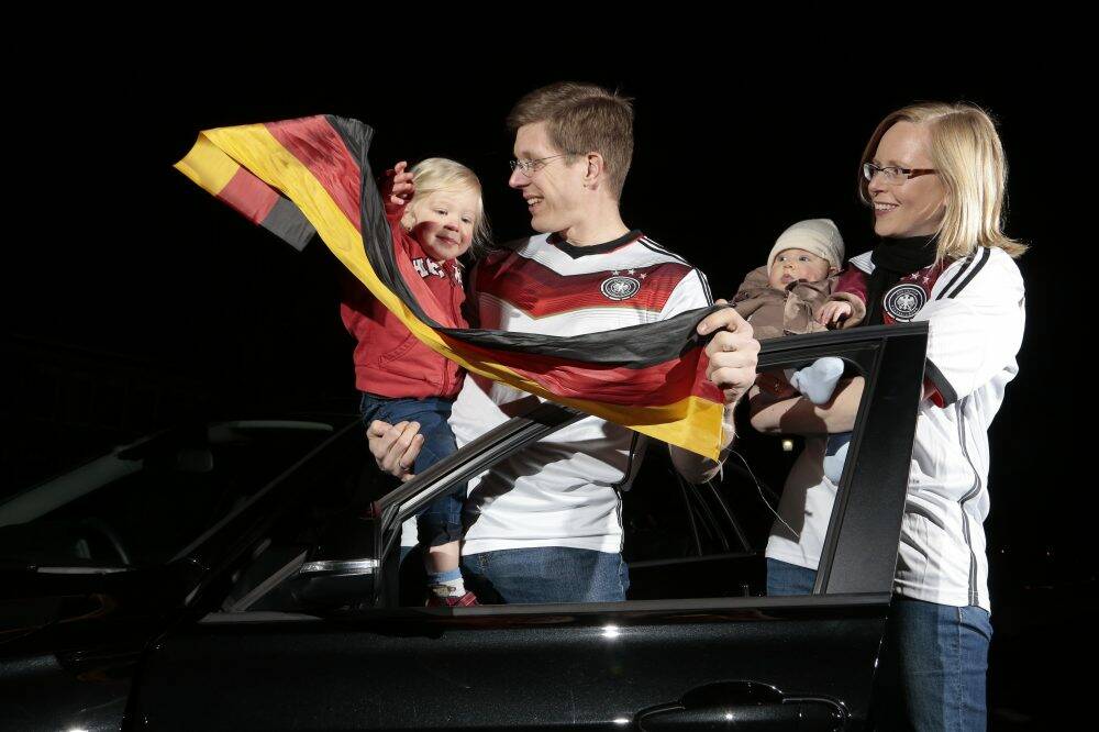 From left, Jonna Olberg, 2, helps dad Lars Olberg, with Finja Olberg, 4 months, and Susanne Olberg.

decorate his car for the World Cup final between Germany and Argentina.  Photo: Jeffrey Chan