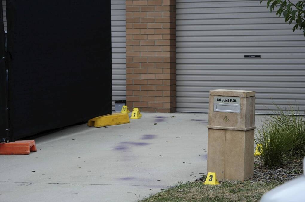 Forensic markers and purple spray paint on the driveway next to the Kambah home where a man was found dead on Wednesday.  Photo: Graham Tidy