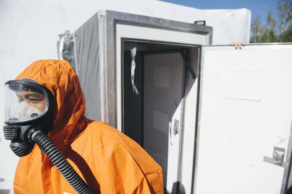 A worker leaves the decontamination area of an asbestos house in Hiles Place, Kambah, that has been shrink wrapped in preparation for demolition. Photo: Rohan Thomson