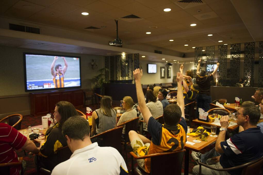 Hawks fans celebrate at the Southern Cross Club after the siren sounds to give the club its third AFL premiership in three years. Photo: Rohan Thomson