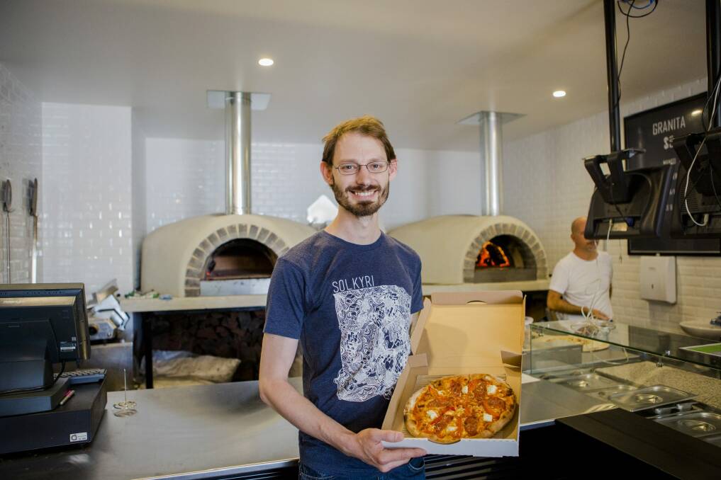 Happy customer Dax Liniere of Gold Creek with one a customised pizzas from 10" Custom Pizzeria. Photo: Jamila Toderas