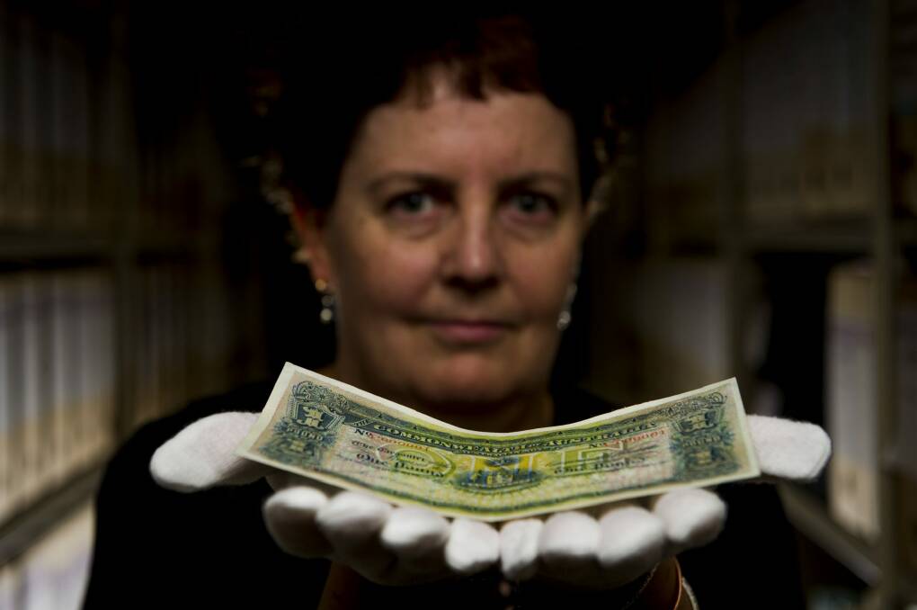 One worth a million: NLA Curator of Manuscripts Kylie Scroope holds the rare one pound. Photo: Jay Cronan