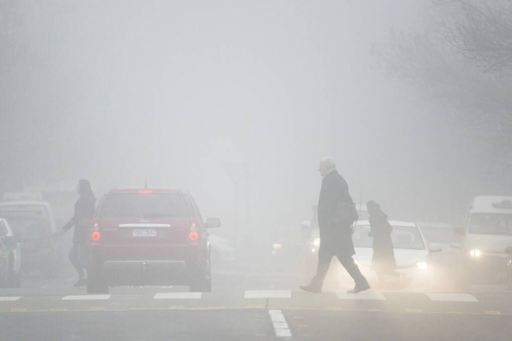 Pedestrians make their way through the fog in Canberra. Photo: Rohan Thomson