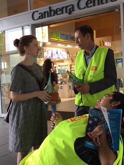 Greens MLA Shane Rattenbury sells The Big Issue with vendor Tau while speaking to a prospective customer. Photo: Supplied
