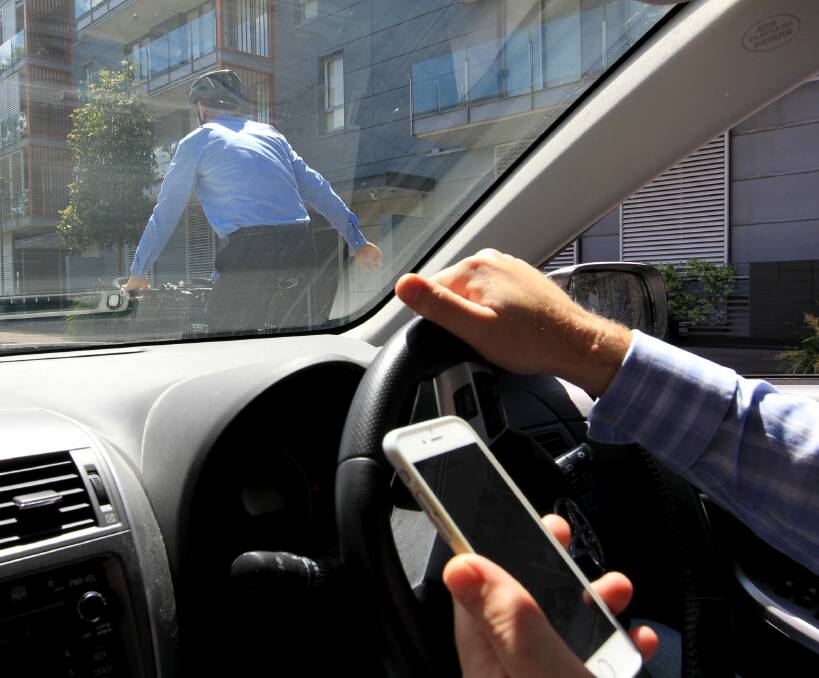 Drivers face $400 fines and 3 demerits if caught using their phones like this behind the wheel. Photo: Janie Barrett