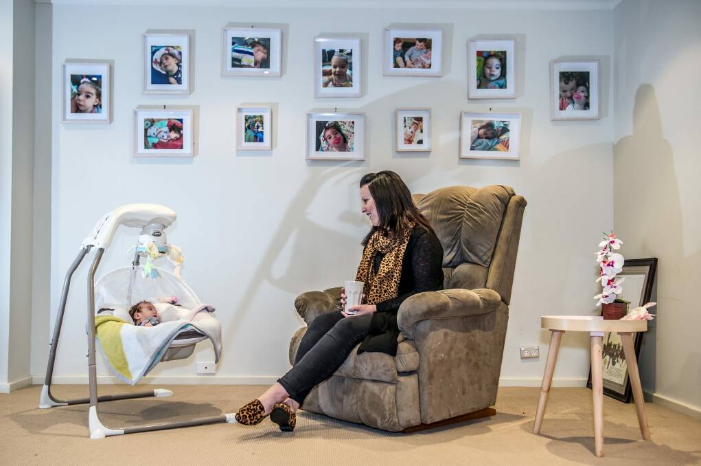 Jerrabomberra's Melissa Agius with baby Loralei under a wall of photographs of her older daughter, Alexis. Photo: Karleen Minney