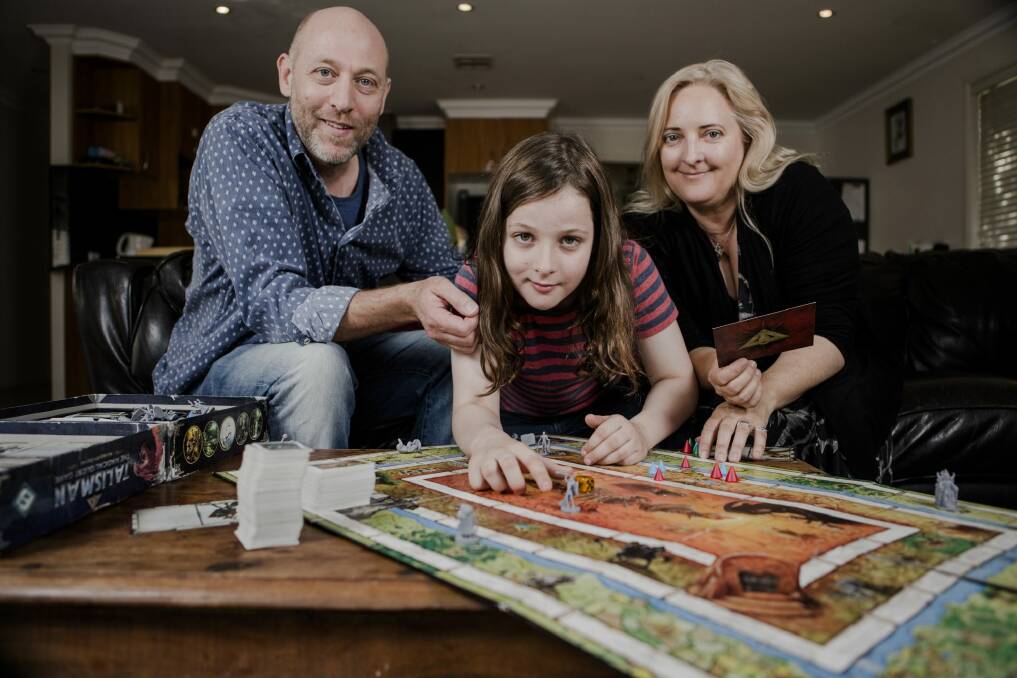 Canberra's littlest heavy metal guitar player Callum McPhie with parents Doug McPhie and Melissa Freeman at their north Canberra home. They love playing board games together. Photo: Jamila Toderas
