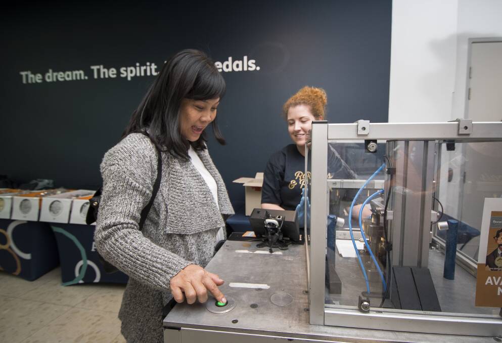 Nhan Nguyen from Sydney with legends and events co-ordinator, Claire Wiscombe, using the mobile press at the Ratbags and Rascals Roadshow Reveal at the Royal Australian Mint. Photo: Elesa Kurtz