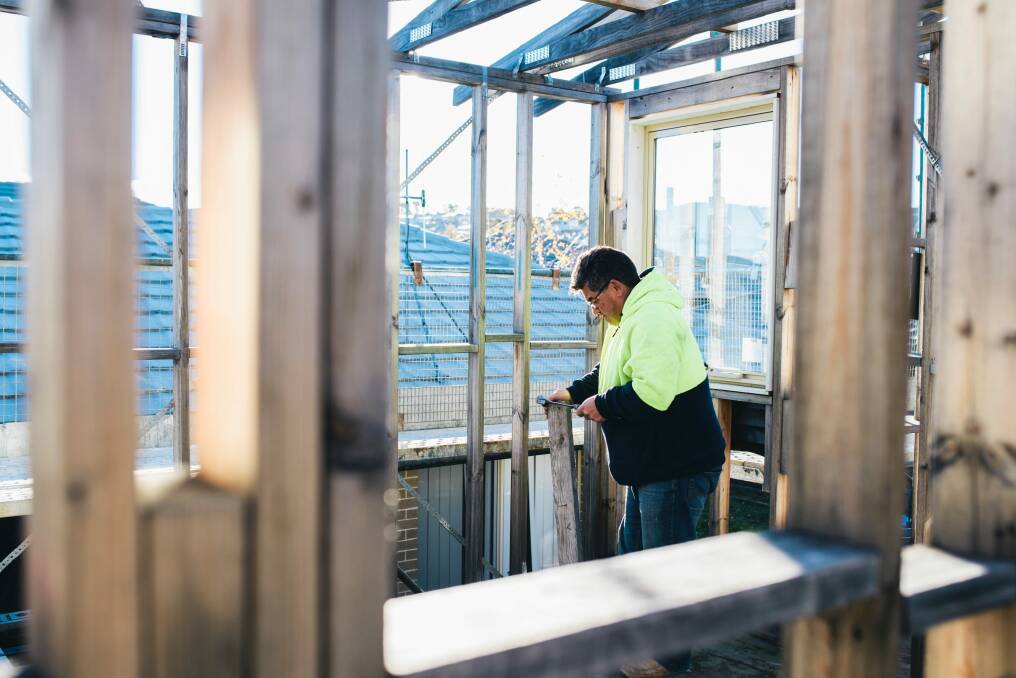 Labourer George Nanos working on an unfinished home in Casey. Housing growth Photo: Rohan Thomson