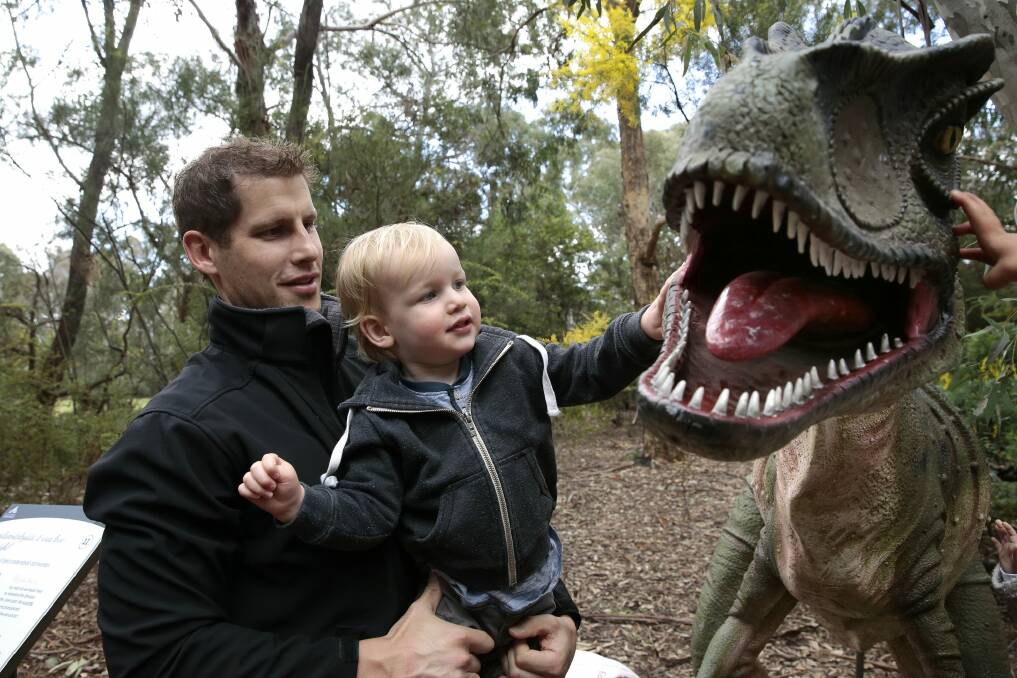 Tim McGrath and son Arthur, 1, of Weston get up close and personal with Australovenator during National Science Week.    Photo: Jeffrey Chan
