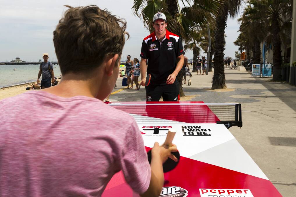 St Kilda footballer Paddy McCartin plays a game of pop-up table tennis against Saints fan Oliver Diano at St Kilda beach. Photo: Chris Hopkins