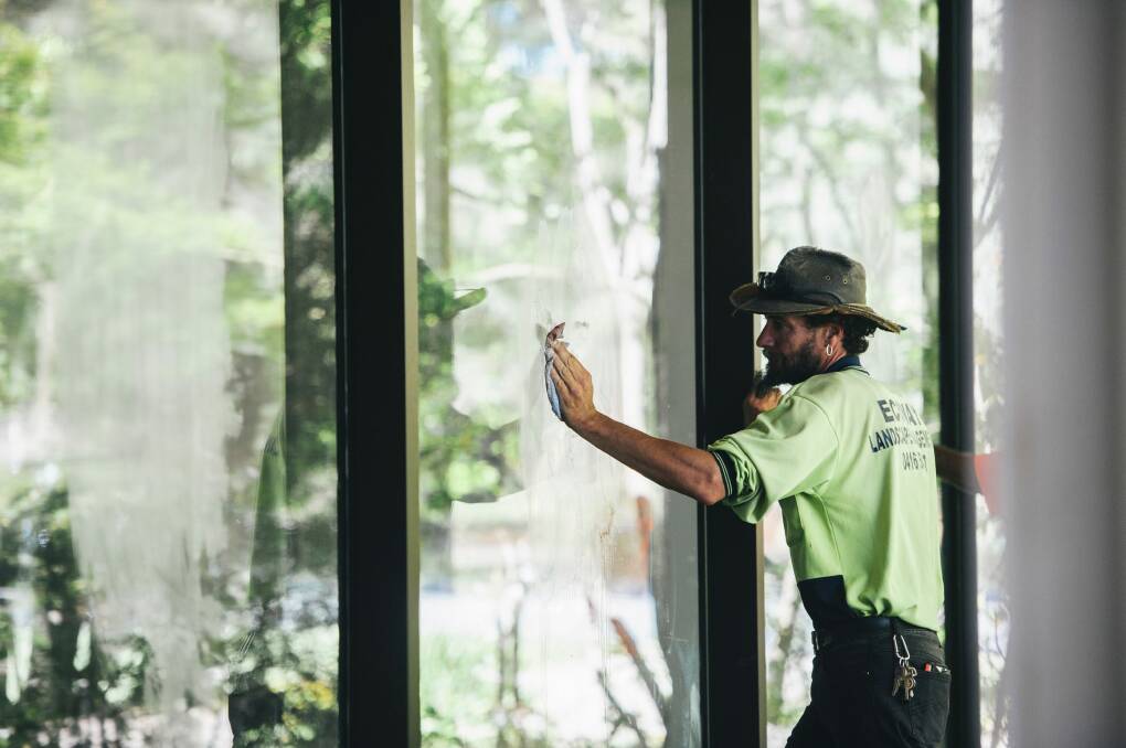 Workers clean Indigenous signs from the building's windows. Photo: Rohan Thomson