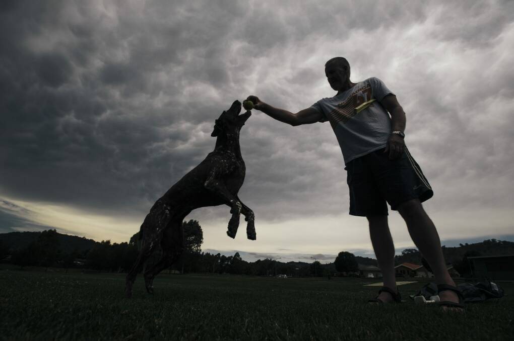 Banks resident Ian Foster and his dog, Jess, underneath mammatus clouds in Tuggeranong on Tuesday afternoon. Photo: Rohan Thomson