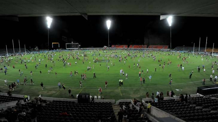 Patrons on the field after an AFL NAB Cup match between the GWS Giants and Essendon Bombers at Manuka Oval under lights. Photo: Graham Tidy