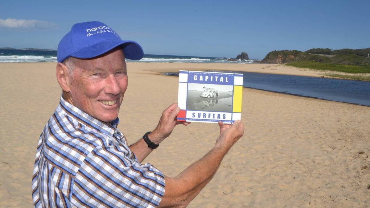 Ian Ingram with his new book Capital Surfers on Narooma main surf beach, the exact location where he was photographed with his VW Beatle in 1964, featured on the front cover. Photo: Supplied