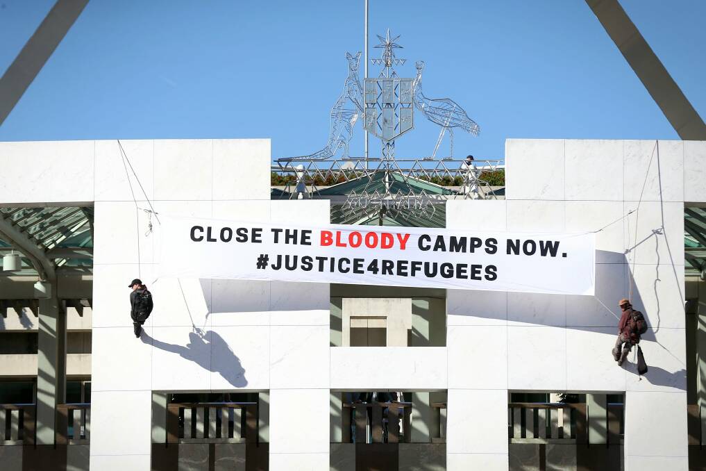 Two protesters unfurl a banner on the Parliament House building in December 2016. Photo: Alex Ellinghausen