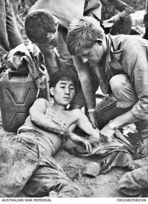 Major Geoff F. Cohen and Corporal D. F. Butler, both members of 3rd Battalion, The Royal Australian Regiment (3RAR), dress the wounds of a North Vietnamese soldier. Photo: AWM