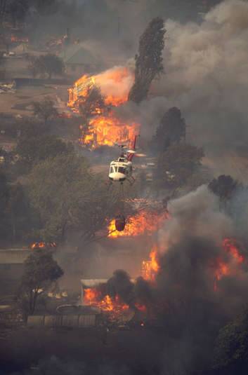A helicopter waterbombs houses burning at Uriarra at about 1.30pm on January 18, 2003. Photo: Neville Dawson