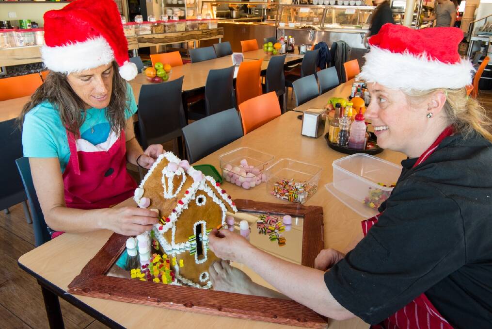 Davis' Marine Science Technician, Kim Picard (L), helps decorate the Christmas gingerbread house with Station Chef, Kerry Oates (R). Photo: Barry Becker/Australian Antarctic Division