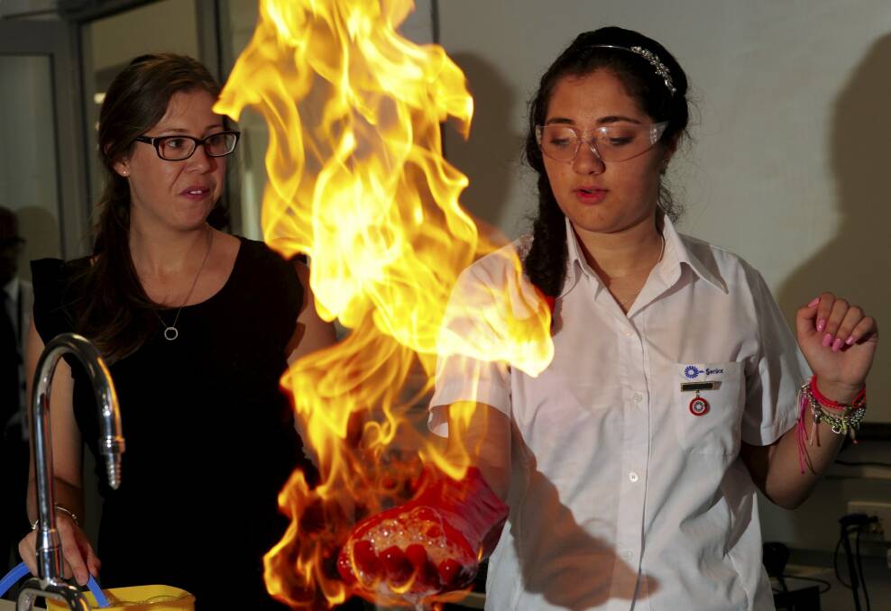 Harrison School year 10 student Zahra
Moinkhah experiences the methane fire bubbles experiment, under
the watchful eye of science teacher Laura Simsen. Photo: Graham Tidy