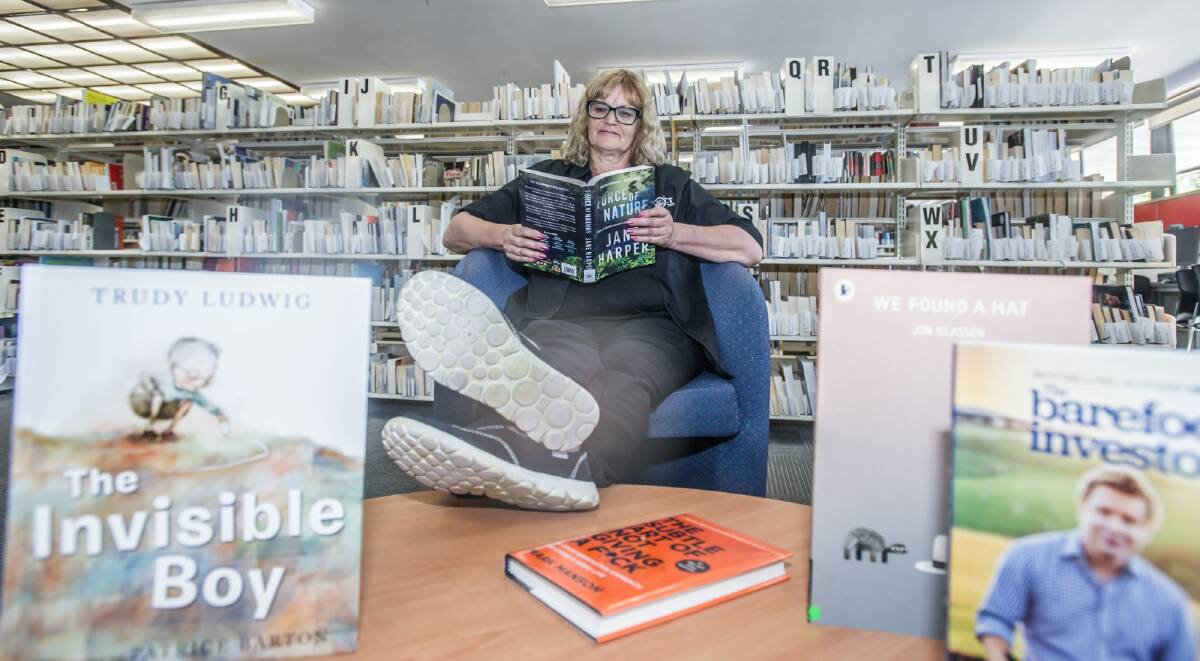 Dickson library customer service officer Cassie Carey with some of the library's most borrowed books for 2017. Photo by Karleen Minney. Photo: Karleen Minney