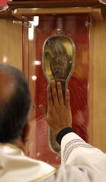 Father Francis Kolenchery  administrator of St Christopher's Cathedral says a prayer with the relic of St Francis Xavier. Photo: Jeffrey Chan