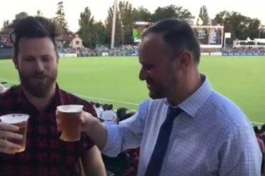 Chief Minister Andrew Barr skolls a beer in front of the Bob Hawke stand. Photo: Hit 104.7