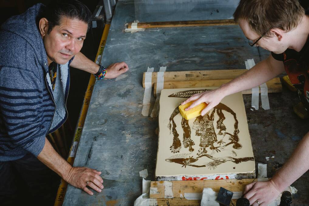 Artist Arone Meeks watches Megalo press studio manager John Hart with a lithograph. Photo: Sitthixay Ditthavong
