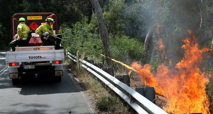 ACT Parks and Conservation firefighters Gareth Conway and Lowell Steffen uses the 'Phoenix' Flame Thrower during a Hazard Reduction Burn along Black Mountain Drive. Photo: Jeffrey Chan