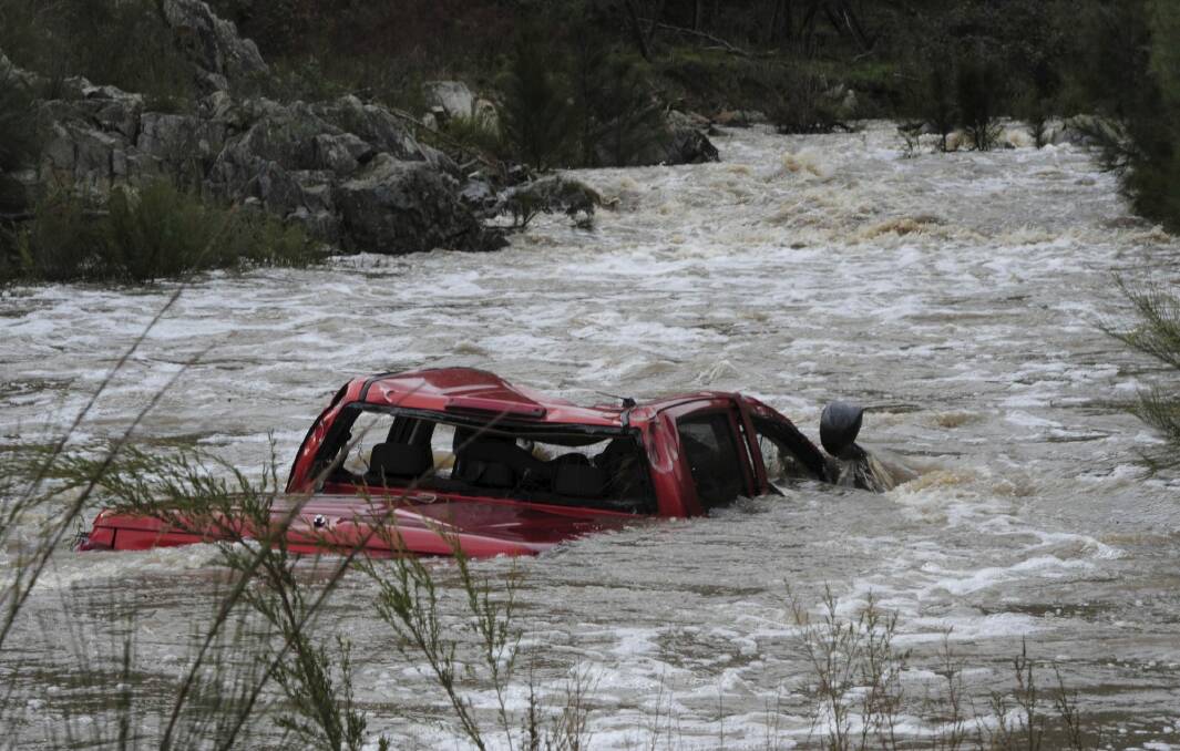 The ute driven by the Canberra man remains partially submerged in the swollen river. Photo: Graham Tidy