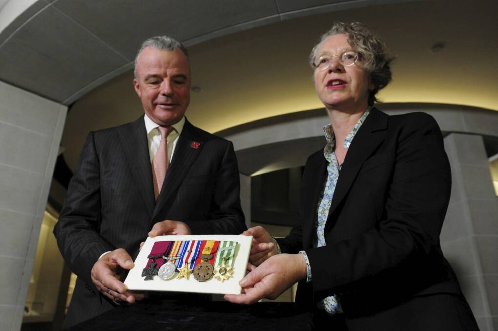 Australian War Memorial director Brendan Nelson receives the Victoria Cross and cluster of medals belonging to the late Peter Badcoe from Mandy Paul. Photo: Graham Tidy