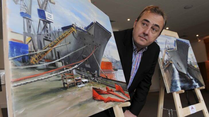 Artist Peter Churcher poses with two of his paintings of the yet-to-be-completed HMAS Canberra being constructed in Spain. The paintings will eventually go on display at the Australian War Memorial. Photo: Graham Tidy