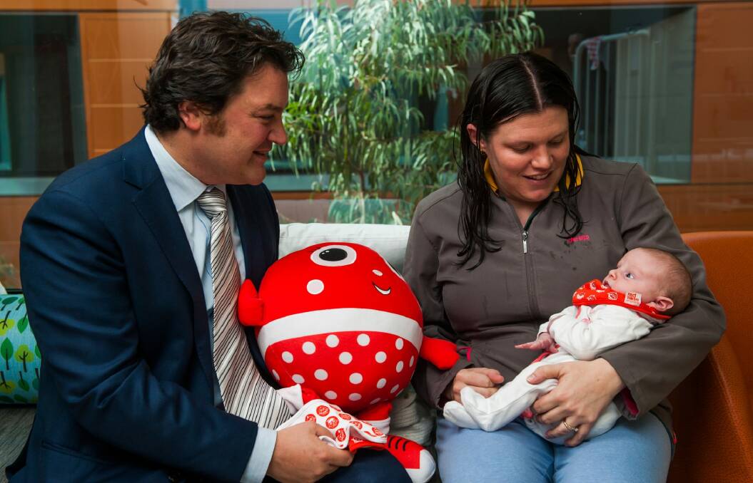 Kathleen Garvie of Crace with 24-day-old daughter Ivy-Rose receives a Sids and Kids's Red Nose Day bib from ActewAGL CFO, Steven Skourakis. Photo: Elesa Kurtz