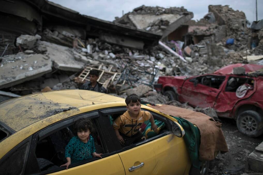 Children play inside a damaged car, amid heavy destruction in a neighborhood recently retaken by Iraqi security forces from Islamic State militants on the western side of Mosul, Iraq. Photo: AP Photo