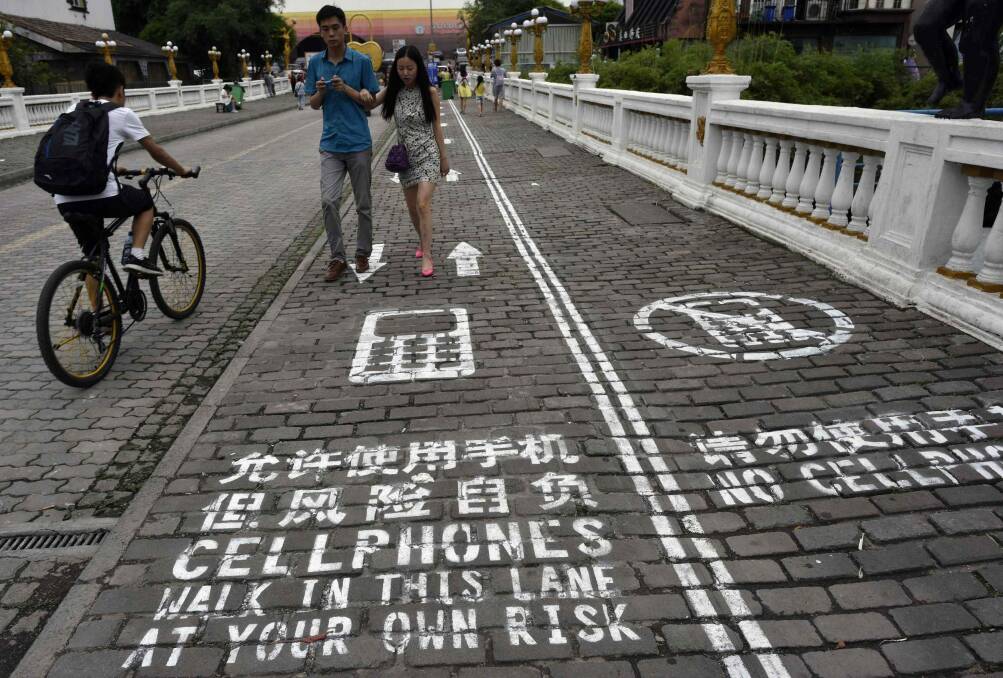 Pedestrians walk down a footpath in Chongqing in China divided into two sides - one marked with "Cellphones walk in this lane at your own risk" and the other "No cellphones", as an attempt to reduce pedestrian incidents, local media reported.  Photo: Reuters