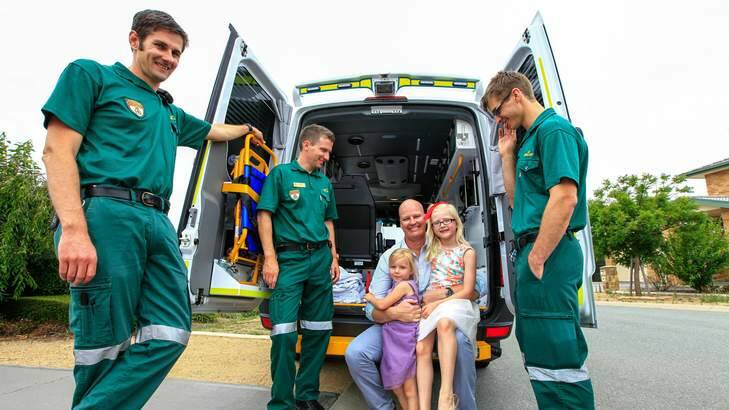 Kurt Fountain receives a hug from his children Sybella age 3 and Charlotte age 6 with paramedics Ben Grellman, Michael Hamill and Mark Molloy. Photo: Katherine Griffiths