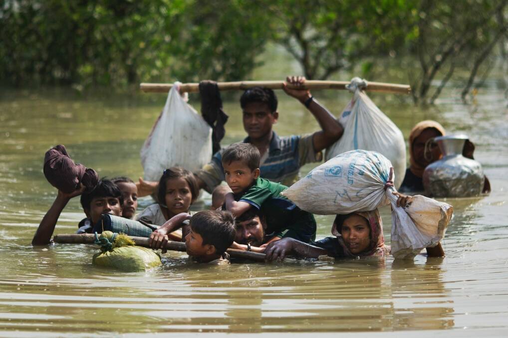 A Rohingya family fleeing Myanmar reaches the Bangladesh border after crossing a creek. Photo: Bernat Armangue